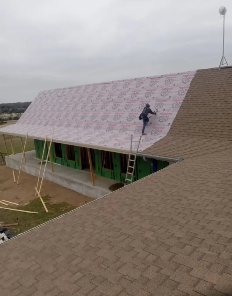 Worker preparing underlayment for a metal roof installation in San Bernardino